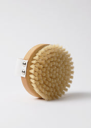 Natural wood and bristle round body brush with practical webbing for ease of use in your bodycare rituals, in a beautiful quality gift box traditionally made for Djusie.