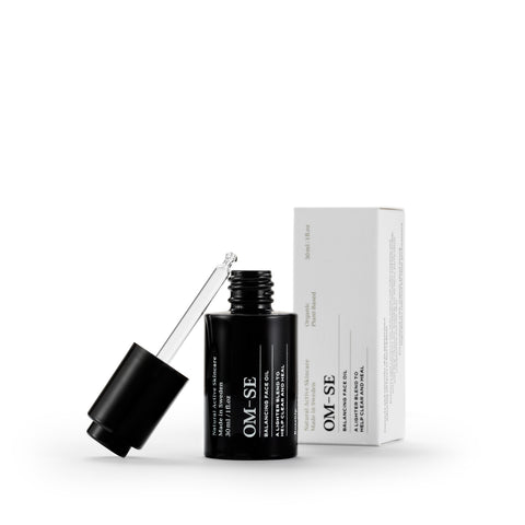 Sleek black glass bottle with stark white text in luxury white packaging creates a stylish minimalist skincare line from OM-SE. This balancing facial oil is vegan and totally organic for easy beauty routines, ideal for acne skin problems.